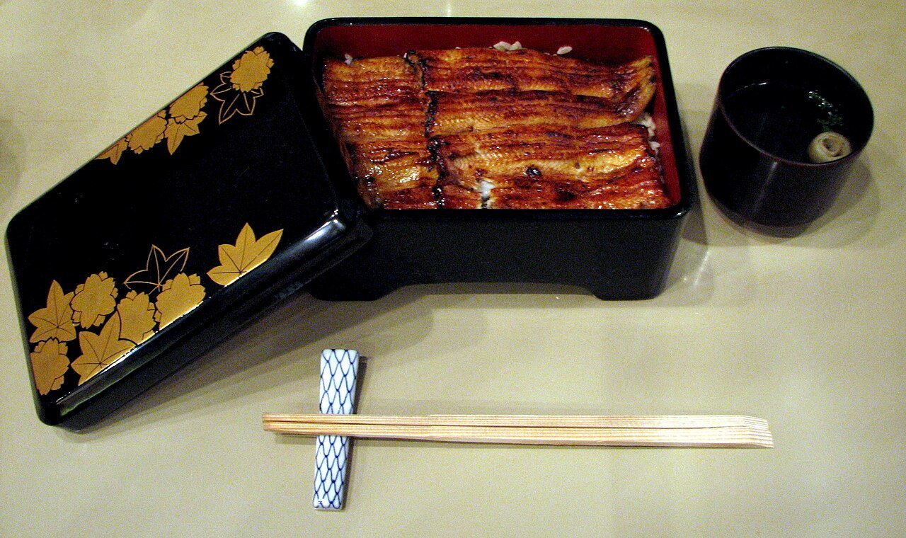 蓋付きの黒漆の重箱に盛られたうな重（浜名湖うなぎのイメージ）