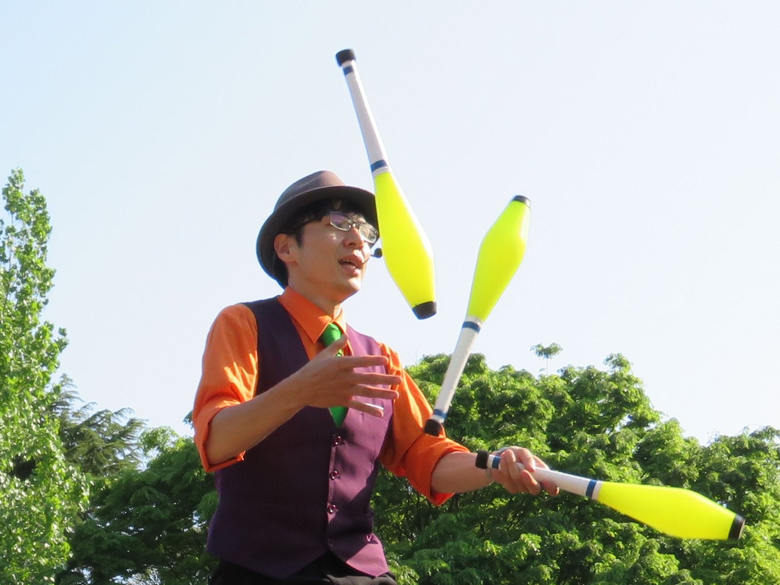 一輪車の上でクラブジャグリングを披露する大道芸人