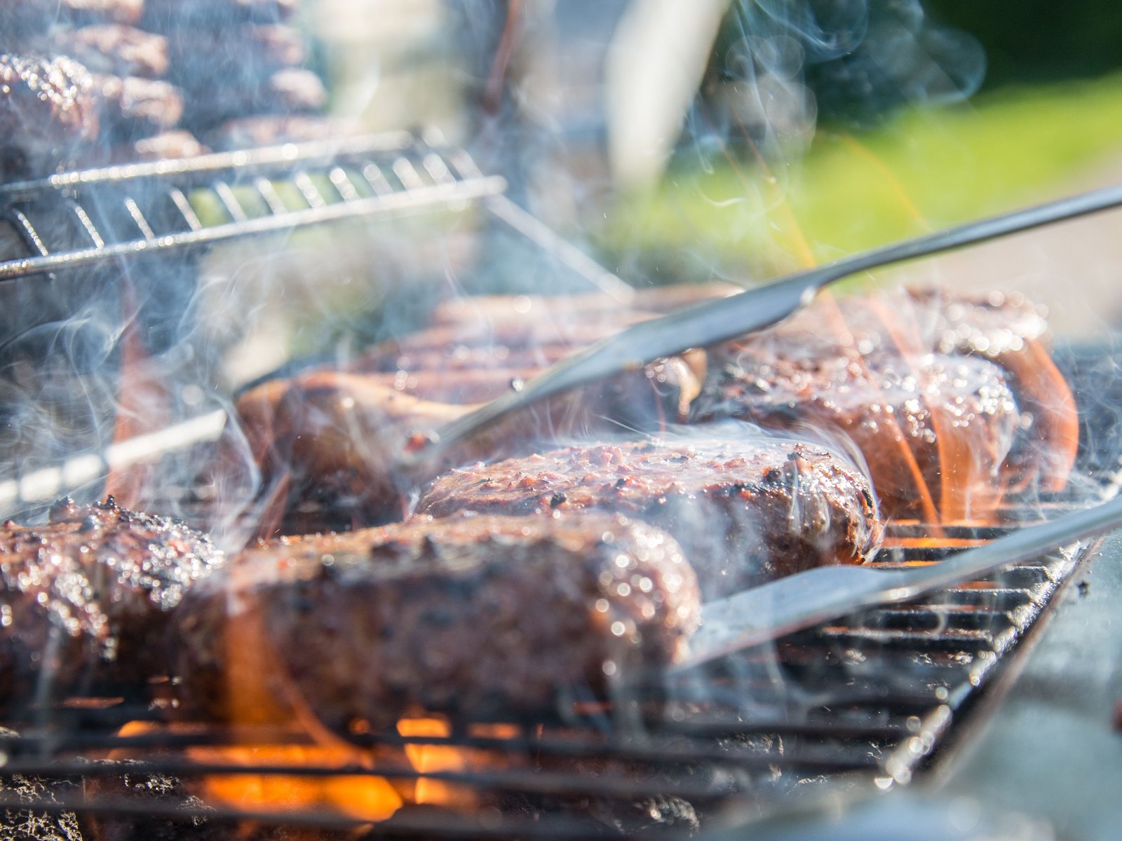 炎と煙を上げて網の上で焼けるステーキ（手ぶらBBQのシズルイメージ）