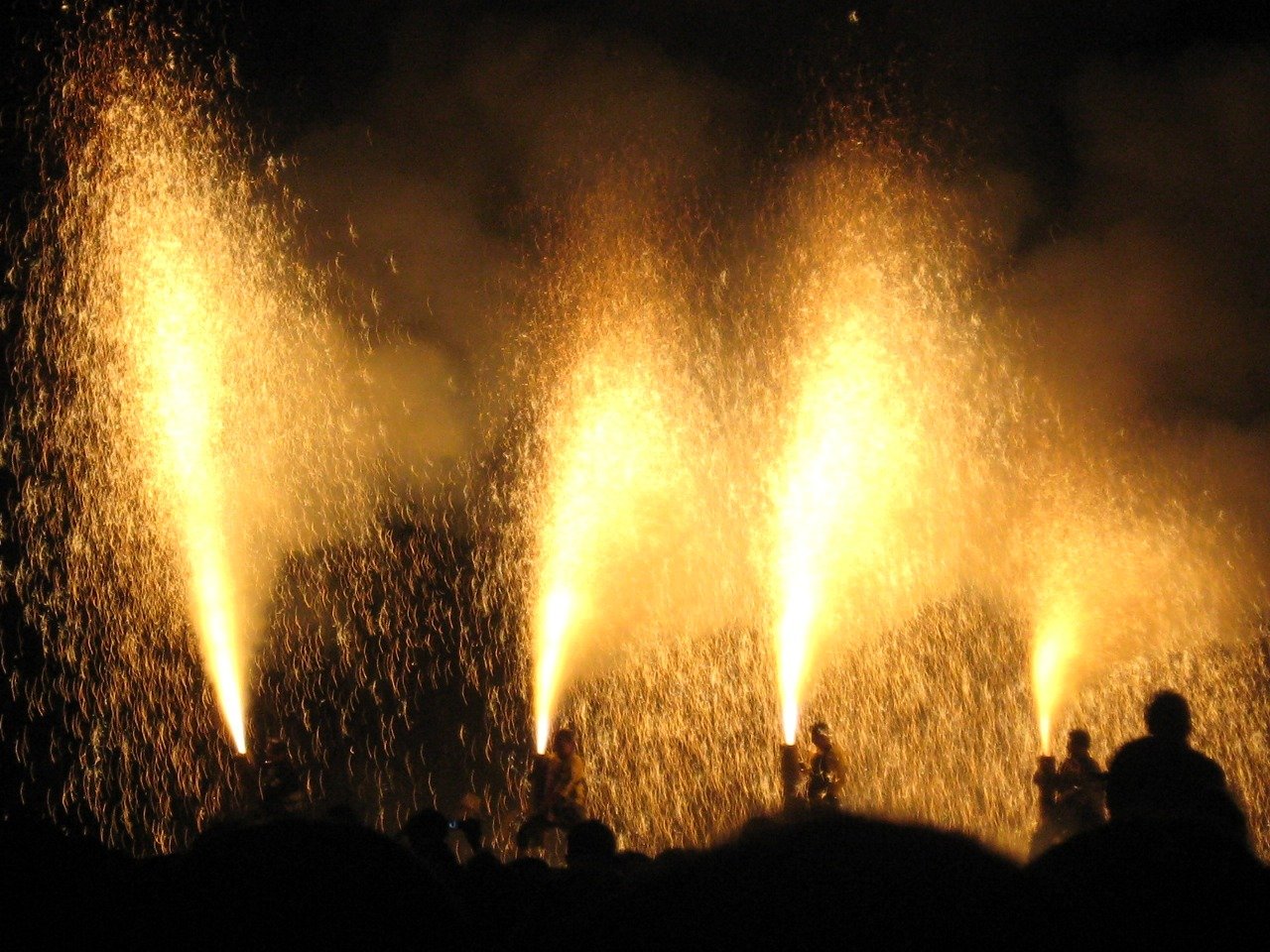 夜、火柱を上げながら手筒花火を抱える人々