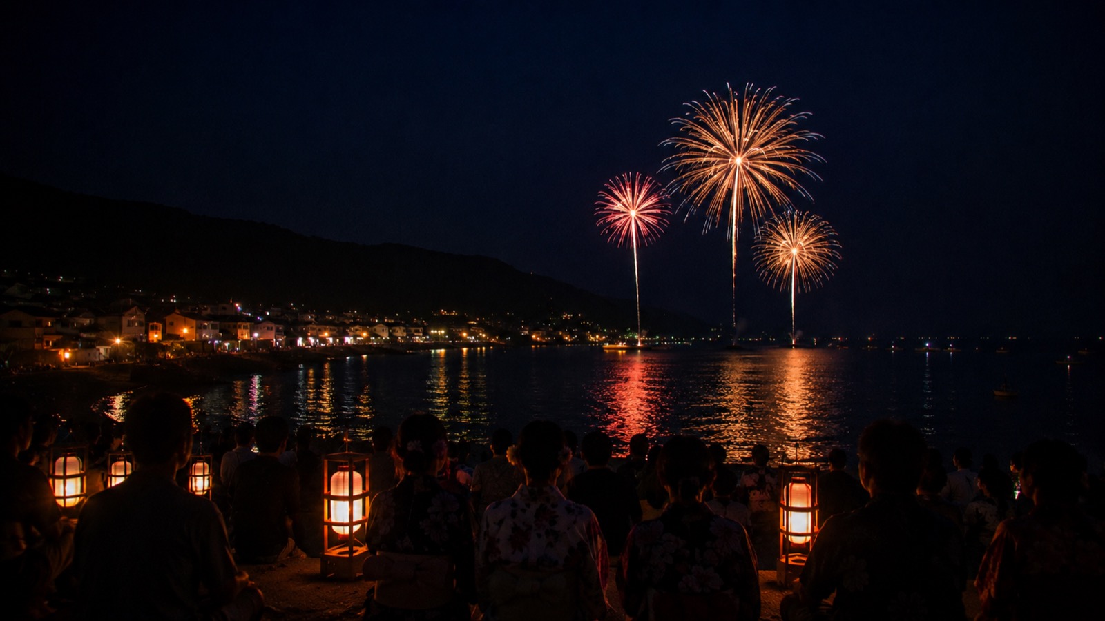 お盆の夜、海辺の町の海上に上がる花火と提灯のあかり、浴衣の人々のシルエット